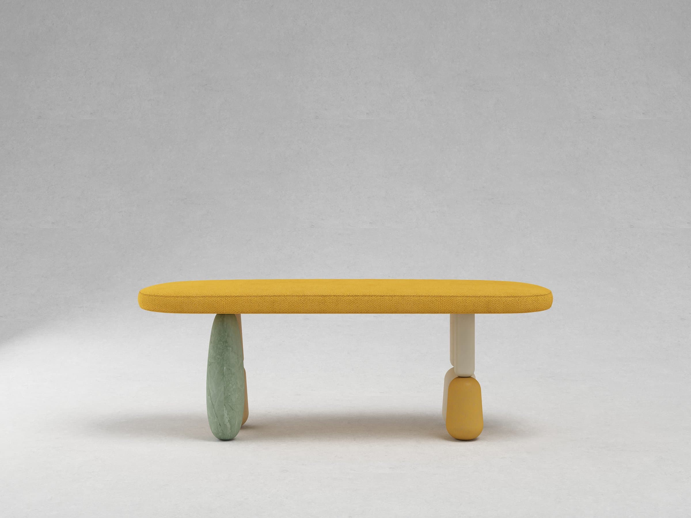 Long mustard boucle bench on four mismatched pill-shaped legs in wood, green marble, ivory, and mustard