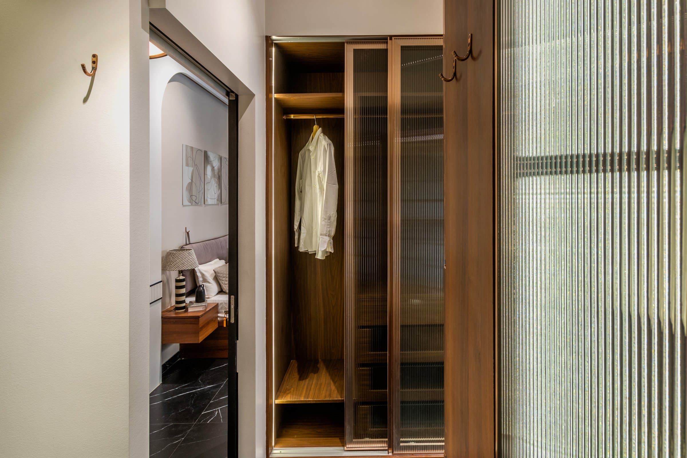 Fluted glass wardrobe doors in a walnut dressing corridor, black marble flooring, Aundh Pune bedroom