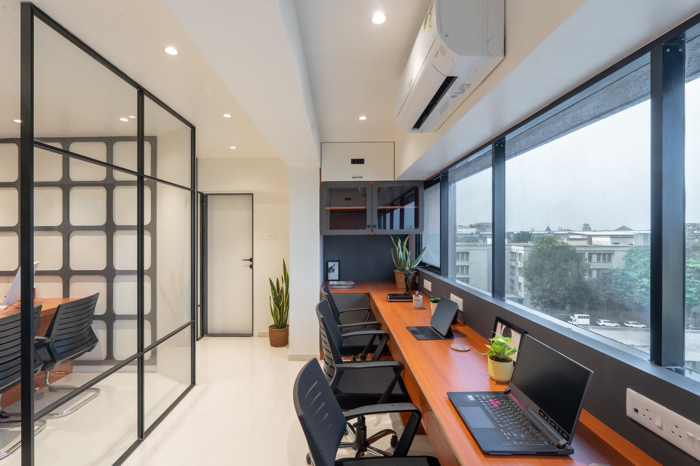 Main chamber desk view with a black mesh chair, backlit wood-panelled bookshelf styled with law volumes and small sculptures, angled cabochon-textured wall behind