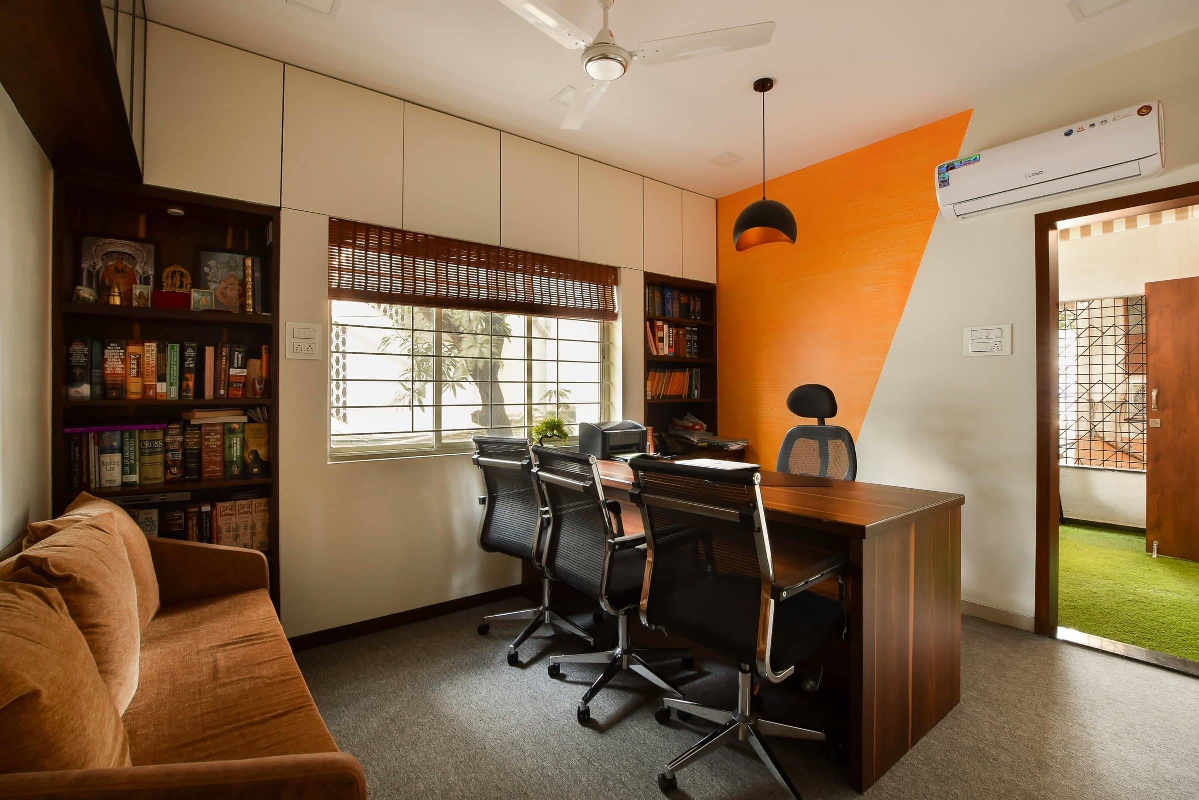 Reception desk with "Deepak Deshpande & Associates" wood signage, teardrop pendant lights, corner plant