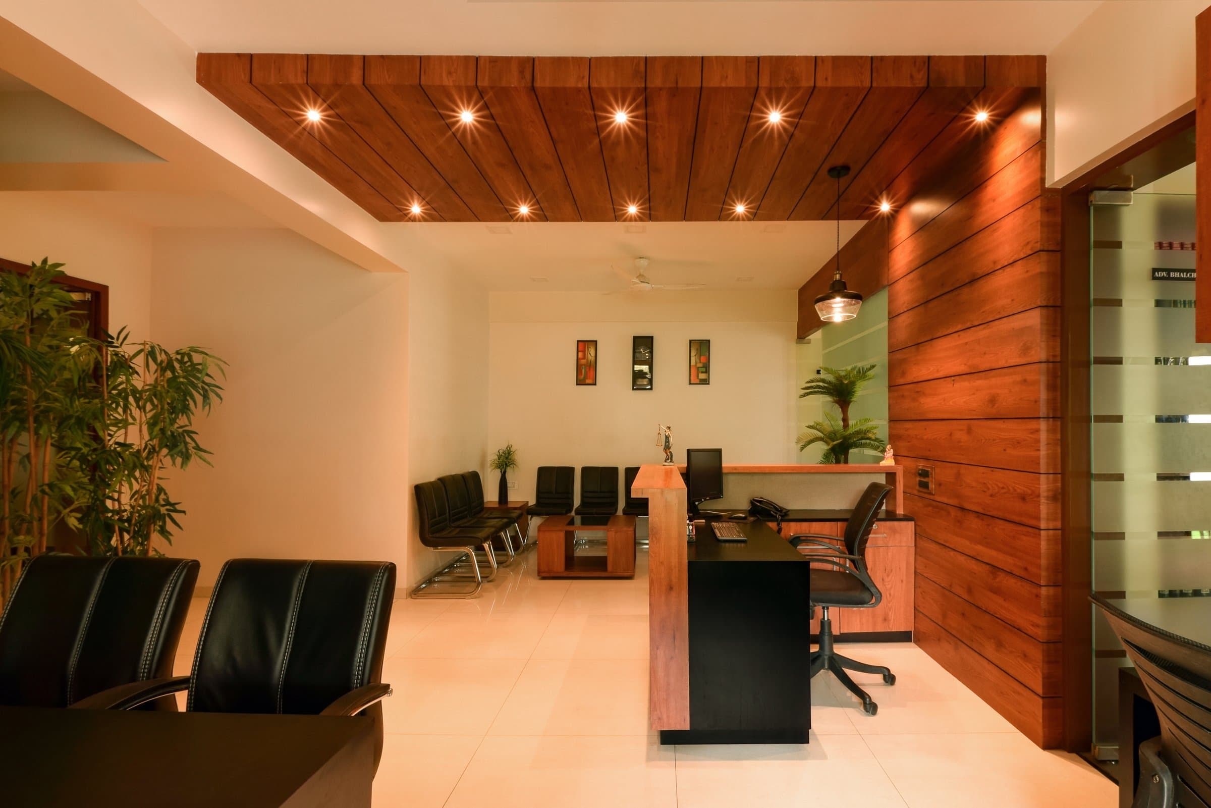 Cabin with a mustard-orange wall, walnut wall cabinet, black leather chairs around a black desk, windows on two sides